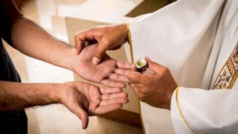 Priest anointing a parishioners hands, similar to what happens at St Francis Xavier and The English Martyrs Parish during the Anointing of the sick